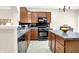 Bright kitchen features a stone countertop island, black appliances, wood cabinets, and an open layout at 6691 Beekman Pl, Zionsville, IN 46077