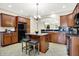 Charming kitchen boasts wooden cabinets, black appliances, a stone countertop island with seating, and views into the living areas at 6691 Beekman Pl, Zionsville, IN 46077