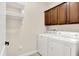 Functional laundry room has tile floors, storage cabinets, a hanging shelf, and updated white washer and dryer units at 6691 Beekman Pl, Zionsville, IN 46077