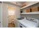 Convenient laundry room with modern appliances, shelving, and access to a half bathroom at 717 Berkeley Dr, Shelbyville, IN 46176