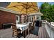 Inviting outdoor deck with dining table, umbrella, grill, and a serene view of backyard at 7341 Washington Blvd, Indianapolis, IN 46240