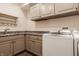 Well-lit laundry room with washer, dryer, granite countertop, sink, and storage cabinets at 7341 Washington Blvd, Indianapolis, IN 46240