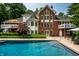 A luxurious pool features steps leading to a brick home with balconies and manicured greenery at 7341 Washington Blvd, Indianapolis, IN 46240