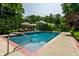 Tranquil backyard pool with lounge chairs, umbrellas, surrounded by mature trees for privacy at 7341 Washington Blvd, Indianapolis, IN 46240