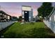 Beautiful twilight view of a spacious backyard featuring a modern house, green lawn, fence, and patio at 806 Shelby St, Indianapolis, IN 46203