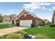 A single-Gathering home featuring a two-car garage, brick facade, and lush green lawn in a residential area at 8115 Cole Wood Blvd, Indianapolis, IN 46239