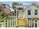 Inviting front entrance with a decorative pergola, yellow gate and door, and white picket fence at 905 Buchanan St, Indianapolis, IN 46203