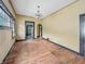 An empty dining room features original wood floors, a traditional chandelier, and cream-colored walls at 1011 W 7Th St, Anderson, IN 46016
