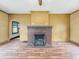 A view of a spacious living area highlighting the brick fireplace, adjacent rooms, and hardwood floors at 1011 W 7Th St, Anderson, IN 46016