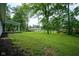 Expansive backyard with mature trees, lush green grass, and a covered patio providing a serene outdoor space at 1015 Fox Hill Dr, Indianapolis, IN 46228