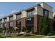 Modern townhome exterior with brick facade, large windows, landscaped patio seating area provides relaxed outdoor living at 11972 Citywalk Dr, Fishers, IN 46038
