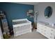 Bedroom with white crib, dresser, and calming blue accent wall at 12389 Titans Dr, Fishers, IN 46037