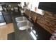Close-up of a stainless steel kitchen sink with a granite countertop and tile backsplash at 12389 Titans Dr, Fishers, IN 46037