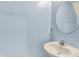A powder room with light blue walls, a round mirror, and a classic white sink at 1571 N Creekwater Pass, Greenfield, IN 46140
