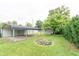 Spacious backyard featuring a carport, a fire pit, a shed, and mature trees at 2249 Maple St, Columbus, IN 47201