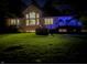 Backyard featuring a well-manicured lawn, a spacious deck, and a hot tub, illuminated by blue lights at night at 23119 Sonoma Ln, Cicero, IN 46034