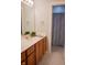 Well-lit bathroom featuring a wood vanity, neutral countertops, and a shower area with a floral curtain at 23119 Sonoma Ln, Cicero, IN 46034