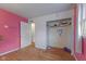 Bedroom with hardwood floors, pink wall, white trim, closet with heart-shaped graffiti, and doorway to another room at 31 Brooklyn Ct, Mooresville, IN 46158