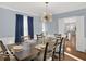 Modern dining room with table set for six, blue drapes and a contemporary chandelier for elegant gatherings at 44 Horseshoe Ln, Carmel, IN 46033