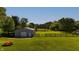Aerial view of outbuilding surrounded by green lawn, a fence, and a cozy fire pit at 453 N 275 E, Columbus, IN 47203