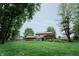 Expansive backyard with lush green lawn, mature trees, and a patio area with seating, ideal for outdoor activities at 46 Hawthorne Ct, Carmel, IN 46033