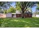 Brick home's spacious backyard shaded by mature trees, complemented by a well-kept lawn and patio area at 5460 N Park Dr, Indianapolis, IN 46220