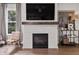 Modern tiled fireplace with dark wood mantel and large television above in the living room at 5917 Bartley Dr, Noblesville, IN 46062