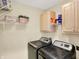 Functional laundry room with washer, dryer, storage cabinets, and shelving for convenience at 6050 Acorn Dr, Columbus, IN 47201