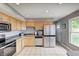 Bright kitchen with stainless steel appliances, light wood cabinets, and neutral tile flooring at 6143 Schoolwood Dr, Indianapolis, IN 46224