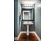 Chic powder room featuring a pedestal sink, wood floors, and an ornate framed mirror and light fixture at 6771 Woodcliff Cir, Zionsville, IN 46077