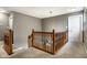 Second floor hallway with wood railing and view looking down to the chandelier below at 6771 Woodcliff Cir, Zionsville, IN 46077