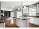Eat-in kitchen with white cabinets, granite counters, and stainless appliances opens to a spacious living room at 6771 Woodcliff Cir, Zionsville, IN 46077