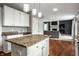Kitchen with white cabinets, granite counters, wood floors, and stainless appliances open to living room at 6771 Woodcliff Cir, Zionsville, IN 46077