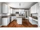 Full kitchen view featuring white cabinets, granite countertops, stainless appliances and wood flooring at 6771 Woodcliff Cir, Zionsville, IN 46077