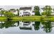 Scenic backyard view with a pond reflecting a charming two-story white home with a deck and mature trees at 6771 Woodcliff Cir, Zionsville, IN 46077