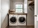 Bright laundry room with washer and dryer, window, wooden shelf, and white walls, offering a clean, efficient space at 7743 Camelback Dr, Indianapolis, IN 46250