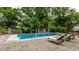 Inviting backyard pool area with brick patio, lounge chairs, lush greenery, and a basketball hoop for outdoor recreation at 7743 Camelback Dr, Indianapolis, IN 46250