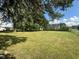 Expansive backyard featuring lush green grass and mature trees, with neighboring homes visible in the distance at 815 N 12Th St, Elwood, IN 46036