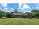 Charming brick home with a beautifully landscaped front yard and lush green lawn under a blue sky at 8818 Mathews Rd, Indianapolis, IN 46259