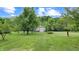 Lush green lawn with mature trees leading to a large outbuilding at 8818 Mathews Rd, Indianapolis, IN 46259