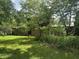 Backyard view of a brick home partially obscured by mature trees and greenery, with a well-maintained lawn at 8875 N Goat Hollow Rd, Mooresville, IN 46158