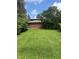 Rear yard featuring green lawn, mature trees, and a brick exterior wall at 8875 N Goat Hollow Rd, Mooresville, IN 46158