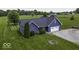 An aerial view shows a blue home with a spacious lawn, driveway, and mature trees at 911 Centennial Rd, Martinsville, IN 46151