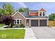 Charming brick home featuring a well-maintained lawn, complemented by a two-car garage and lovely front yard landscaping at 9385 Helmsdale Dr, Indianapolis, IN 46256