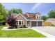 Charming brick home featuring a well-maintained lawn, complemented by a two-car garage and lovely front yard landscaping at 9385 Helmsdale Dr, Indianapolis, IN 46256