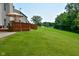 Green backyard with a wood deck, green grass, mature trees, and a view of a pond with fountain at 10601 Adam Dr, Indianapolis, IN 46231