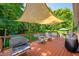 Comfortable back deck features a grill, seating area, wooden railing, and shade covering of the pool at 11059 W Old Nashville Rd, Columbus, IN 47201