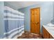 Comfortable bathroom features a shower with a striped curtain, a wooden door, and a vanity at 11059 W Old Nashville Rd, Columbus, IN 47201