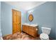 Light blue bathroom equipped with a wooden vanity, toilet, and updated lighting fixtures at 11059 W Old Nashville Rd, Columbus, IN 47201