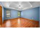 Spacious bedroom with hardwood floors, bright windows, and a tray ceiling with ceiling fan at 11059 W Old Nashville Rd, Columbus, IN 47201